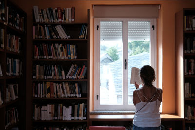 Rear view of woman standing in library