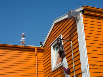 Low angle view of woman against building against clear sky