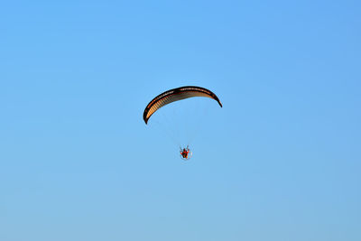 Low angle view of man paragliding against blue sky