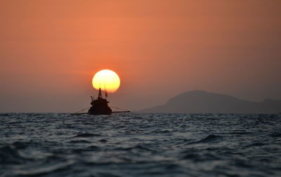 Silhouette boat in sea against sky during sunset