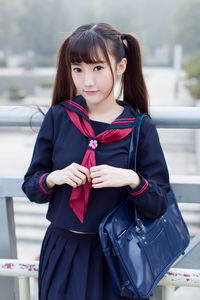 Portrait of woman in uniform standing by railing