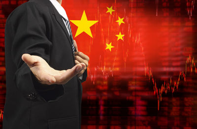 Digital composite image of businessman gesturing while standing against chinese flag