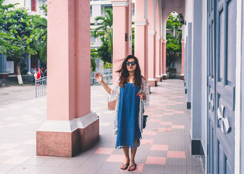 Full length of young woman using mobile phone in city