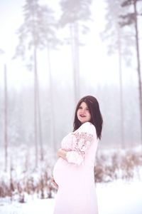 Woman standing in snow against trees during winter