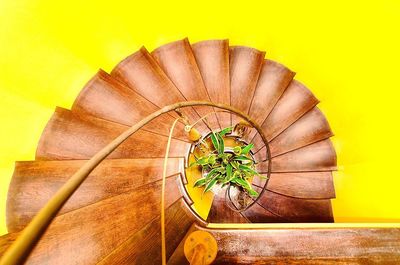 Directly above view of wooden spiral staircase against yellow background