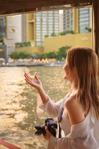 Side view of young woman photographing in city