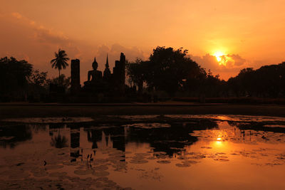 Silhouette buddhist temple against sky at sunset