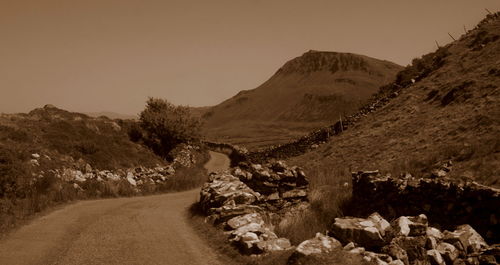 Road leading towards mountains against clear sky