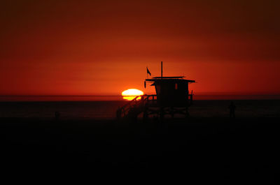 Silhouette lifeguard hut at beach during sunset