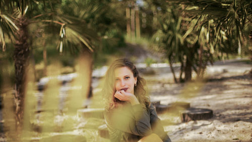 Portrait of smiling young woman against trees