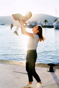 Side view of young woman standing at sea shore