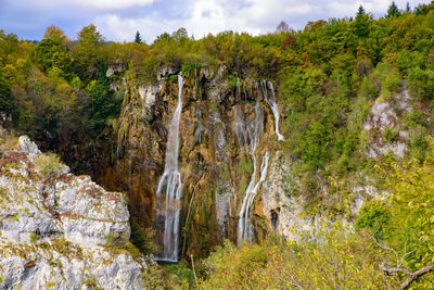 Scenic view of waterfall in forest against sky