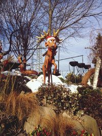 Statue against bare trees against sky