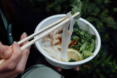 Cropped hand holding noodles with chopsticks