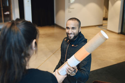 Smiling messenger giving package to female customer