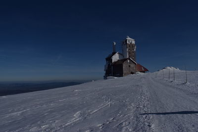 Building on snow covered land against sky