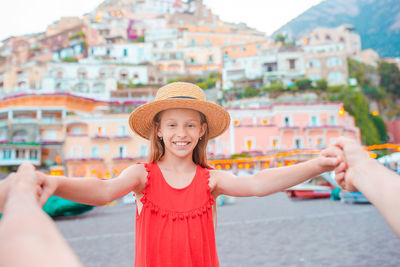 Portrait of happy girl standing against buildings