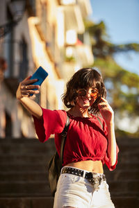 Low angle view of woman doing selfie while standing against building