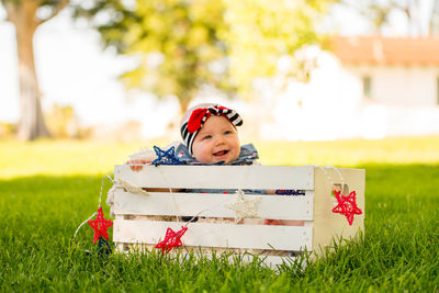 Cute smiling girl in crate on grassy field