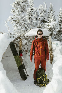 Full length of confident hiker wearing ski-wear while standing on snowy field