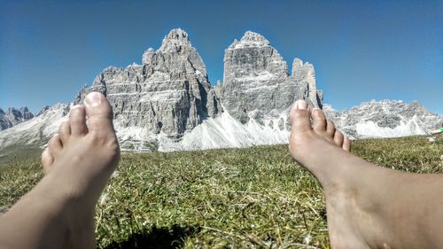 Low section of man on field against mountains and sky