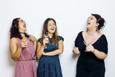 Laughing trendy women celebrating with cocktails