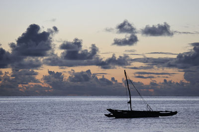 Sailboat in sea against sky during sunset