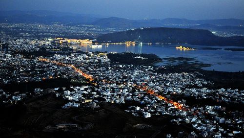 High angle view of illuminated city by sea