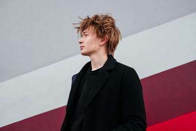 Caucasian young man in black coat looking away outdoors