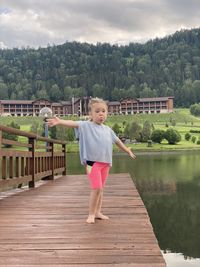 Portrait of girl standing on footbridge over lake