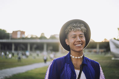 Portrait of happy young man with curly hair wearing hat at park