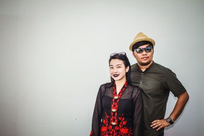 Portrait of young couple standing against white background