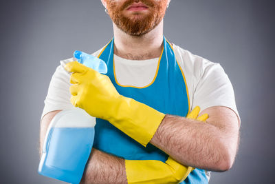 Midsection of man holding umbrella against gray background