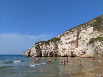 People swimming in sea against sky