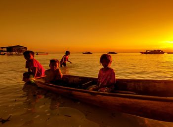 People sitting on beach against sky during sunset