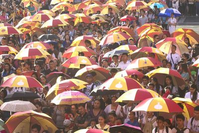 Crowd sheltering under umbrellas watching event