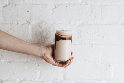 Hand holding coffee cup against wall