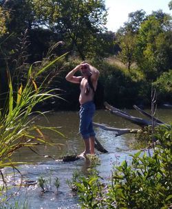 Full length of man standing in lake against trees
