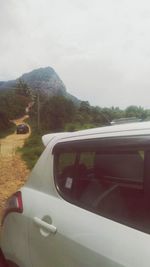 Car on road by mountain against sky