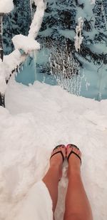 Low section of woman standing on snow covered field