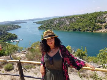 Portrait of woman standing against river