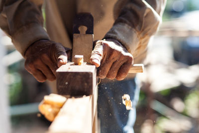 Midsection of carpenter using plane on wood