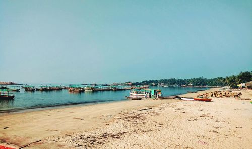 Boats moored on beach against clear sky