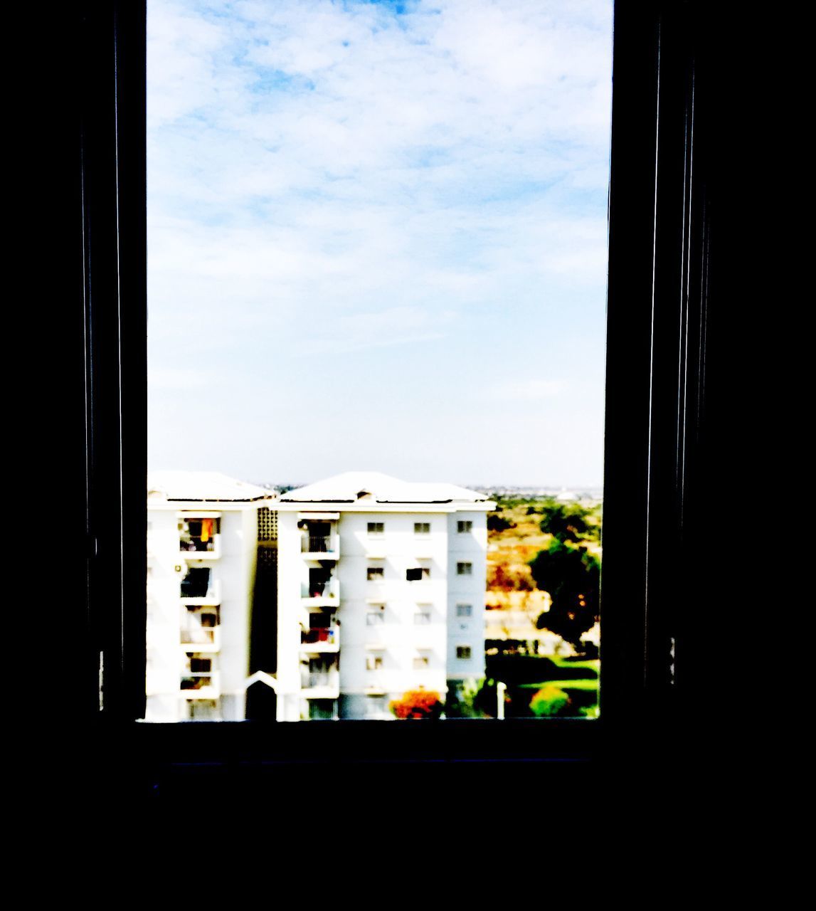 BUILDINGS AGAINST SKY SEEN THROUGH WINDOW