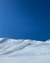 Snow covered landscape against blue sky