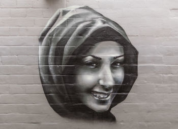 Close-up portrait of woman smiling against wall