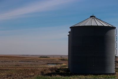 Silo on agricultural field against sky