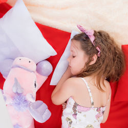At home, full-fledged children's sleep, girl in a sleep mask and pajamas sleeps on red pillows