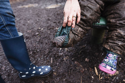 Cropped image of mother holding child's messy pants sitting on slide at park