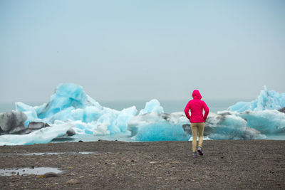 Rear view of person walking on snow covered landscape